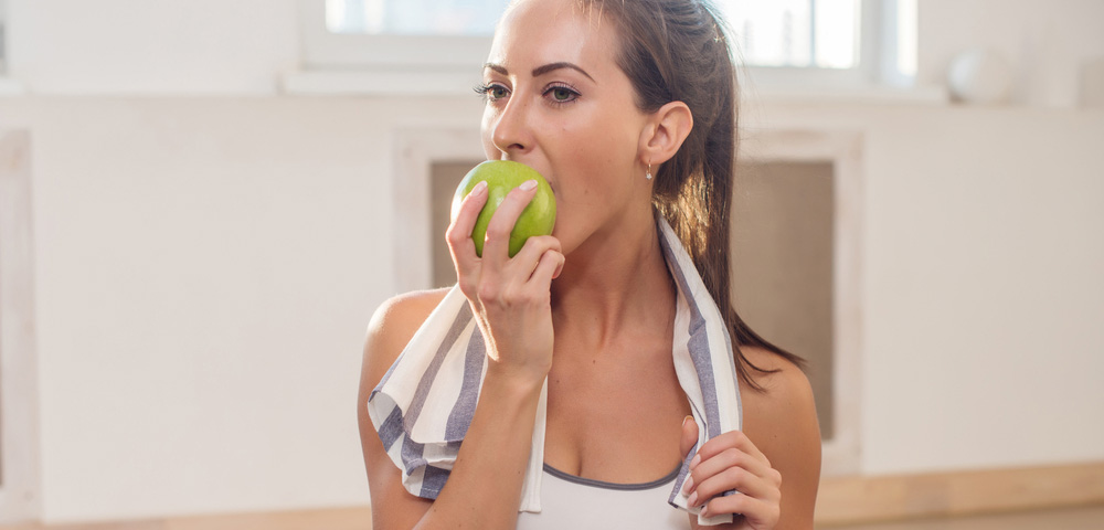 mulher comendo maçã saudável treino academia exercício físico exercícios comida fruta